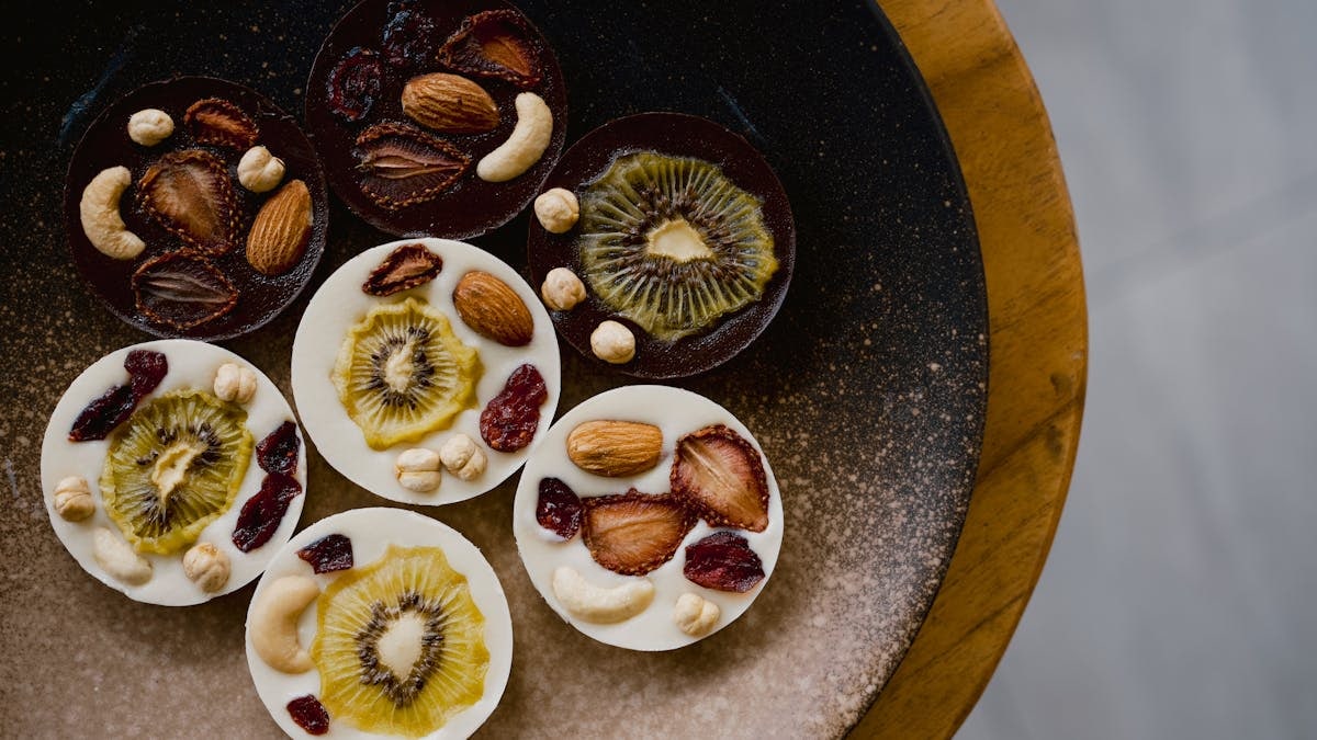 A visually enticing platter of chocolate circles topped with fruits and nuts, a perfect gourmet treat.